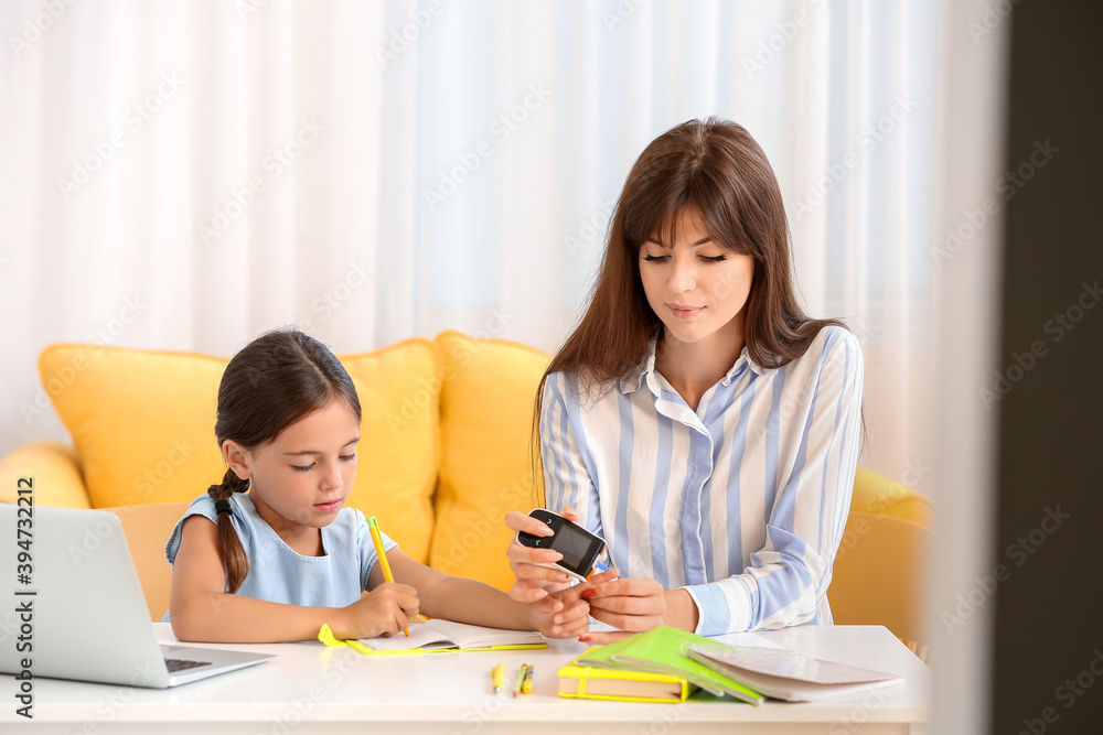 Mother checking blood sugar level of diabetic daughter at home Mother checking blood sugar level of diabetic daughter at home