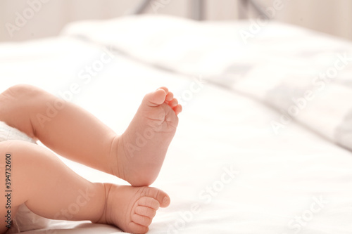 Legs of cute little baby lying on bed