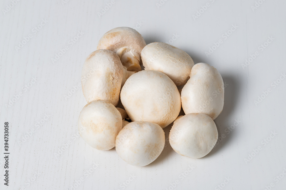 White champignon mushrooms are isolated on a white table. White champignon mushrooms are isolated on a white table.