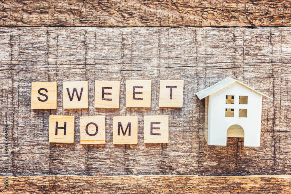 Miniature toy house with inscription SWEET HOME letters word on wooden background. Mortgage property insurance dream home concept. Flat lay top view, copy space Miniature toy house with inscription SWEET HOME letters word on wooden background. Mortgage property insurance dream home concept. Flat lay top view, copy space
