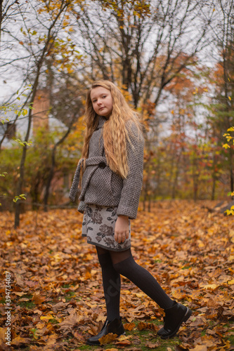 portrait of cute brunette teen girl in gray coat in the autumly forest . Cosiness, autumn