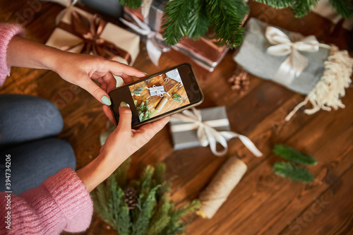 Woman takes pictures of Christmas decor on phone in her hands, focus on phone