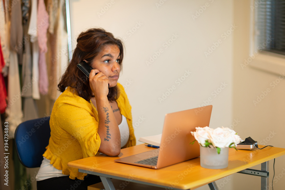 aboriginal woman sitting at desk with laptop computer and telephone aboriginal woman sitting at desk with laptop computer and telephone