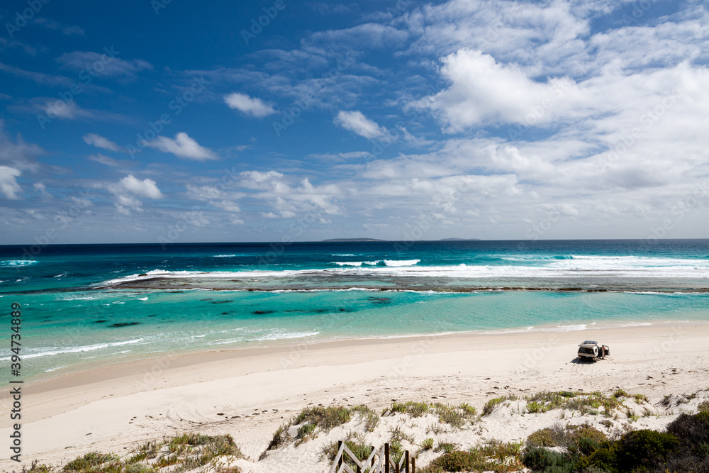 Looking down and out on a view of man with 4wd vehicle on an isolated beach with turquoise lagoon Looking down and out on a view of man with 4wd vehicle on an isolated beach with turquoise lagoon