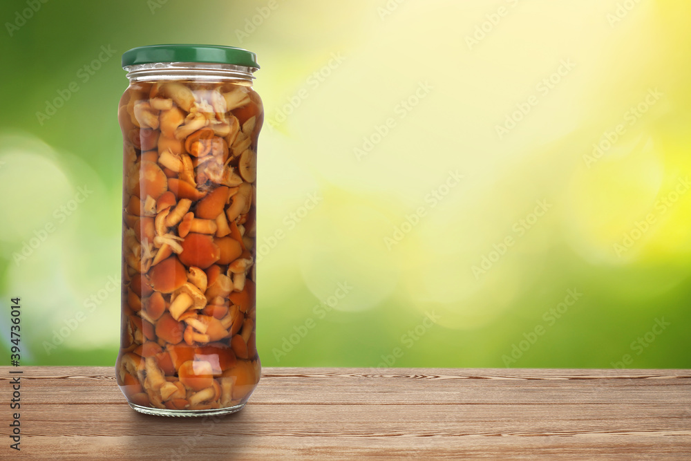 Jar of pickled mushrooms on wooden table against blurred background, space for text Jar of pickled mushrooms on wooden table against blurred background, space for text