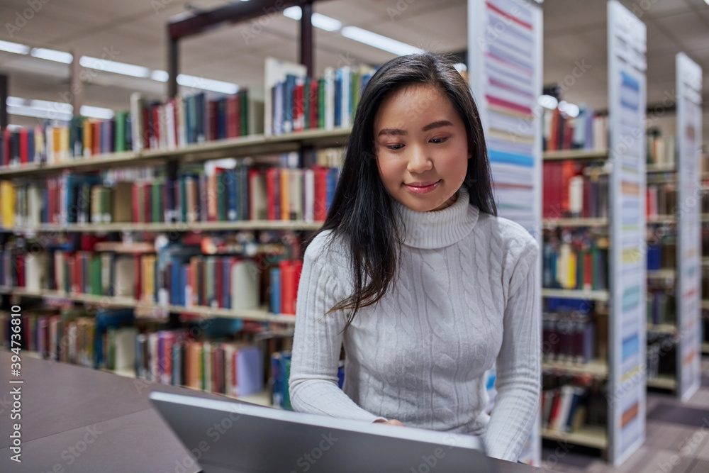 Young female Asian student working on her laptop at university library Young female Asian student working on her laptop at university library