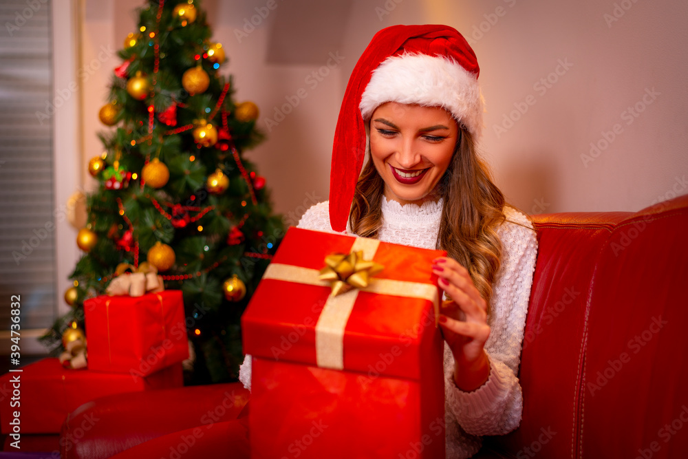 Smiling young woman with christmas present box near christmas tree