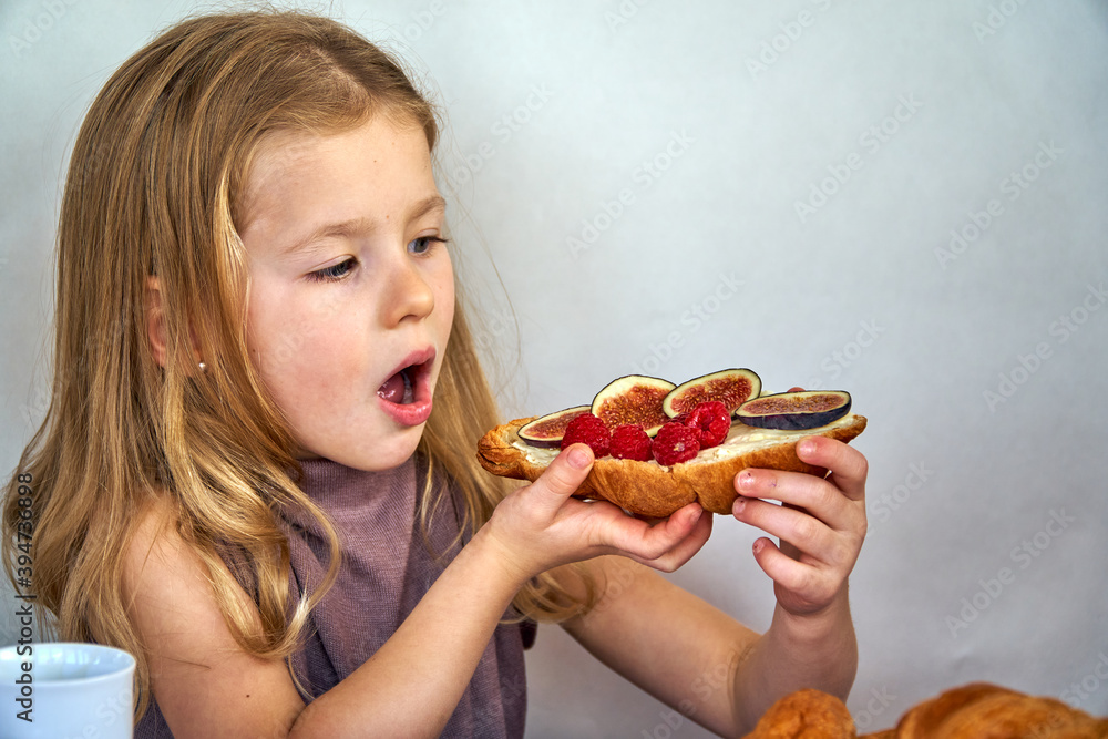 French breakfast sandwich with croissant and figs in the hands of a child girl. Toast with berries French breakfast sandwich with croissant and figs in the hands of a child girl. Toast with berries