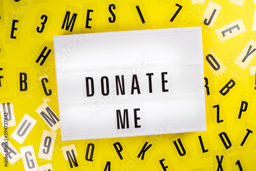 Donate Me text on lightbox on scattered letters background of plastic alphabet. call for charity donations, compassion, philanthropy, Personal assistance to disadvantaged people concept