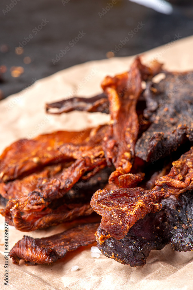 Chicken and beef jerky close-up. Tasty spicy jerky on a dark background, homemade beer snack.