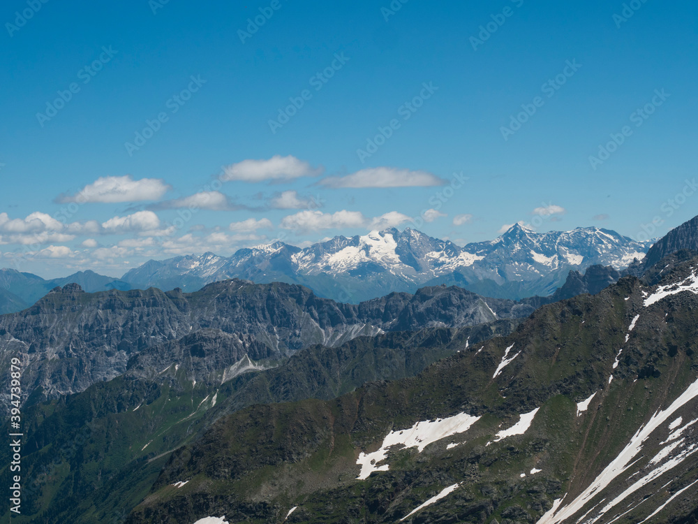 view from Simmingjochl mountain saddle on sharp snow-capped peaks at Stubai hiking trail, Stubai Hohenweg, Alpine landscape of Tyrol, Stubai Alps, Austria. Summer blue sky