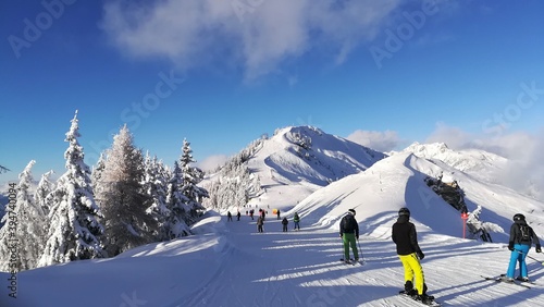 Skiers and snowboarders in the Dorfgastein ski area. Skiing in the austrian alps. Amazing panorama of rocky mountains in winter. Snowy mountain peaks. People play sports in the mountains. photo