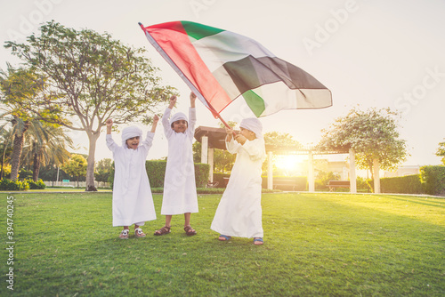 Children playing together in Dubai in the park. Group of kids wearing traditional kandura white dress from arab emirates photo