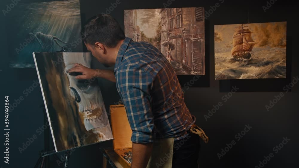 The artist working on the canvas with inspiration in the dark art studio. Drawing process, art therapy, fine art concept. The artist working on the canvas with inspiration in the dark art studio. Drawing process, art therapy, fine art concept.