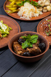 Food set with grilled pork ribs, pickled vegetables, bacon, salad, and moonshine  on black wooden background