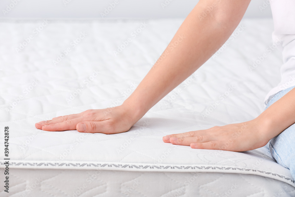 Woman sitting on soft orthopedic mattress, closeup Woman sitting on soft orthopedic mattress, closeup