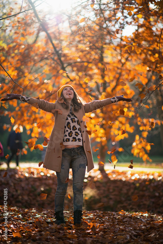 happy stylish woman throws up autumn leaves