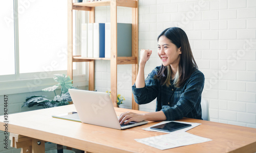 Graphic designer using graphics tablet happy Asian woman freelance worker using computer laptop technology designing innovation creative ideas plan cheering excitement success working modern office © Have a nice day 