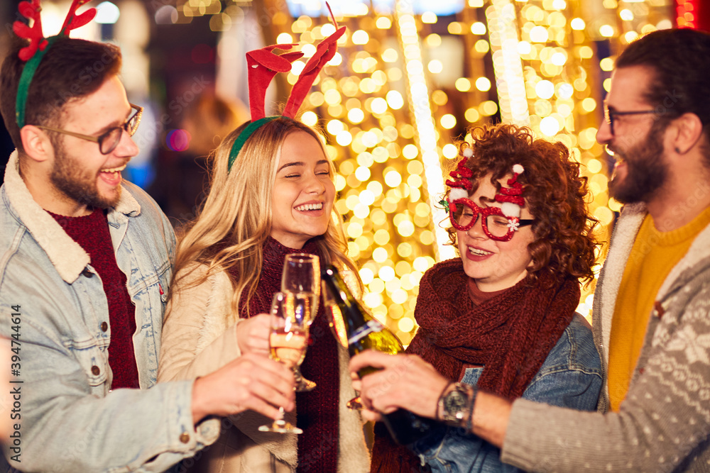 Group of happy friends drinking champagne and celebrating New Year at the street. New year party.