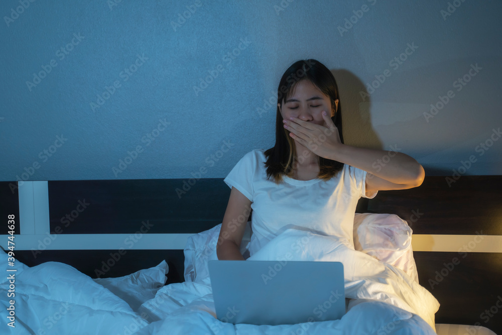 Beautiful Asian woman in bed using computer laptop technology, tired addictive can’t sleep, playing entertainment internet browsing social media website business study, domestic home comfy lifestyle