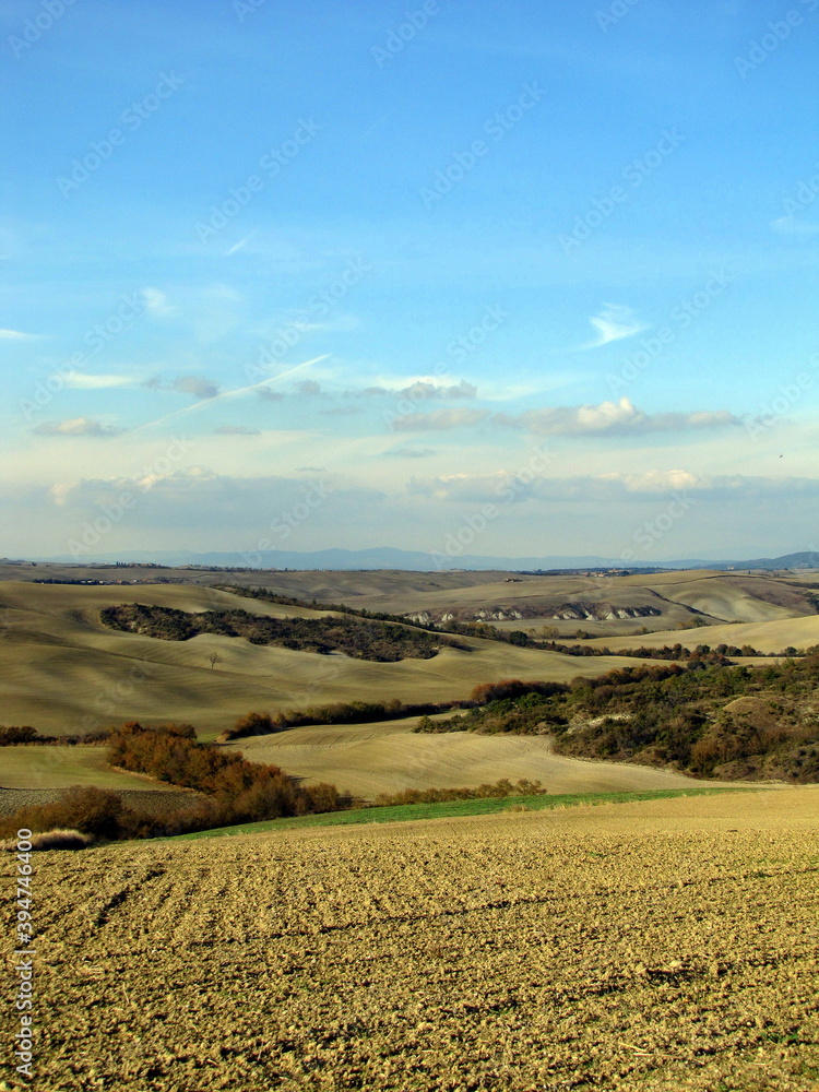 Autumn panorama over the hills of the Val d'Orcia, with clouds and blue sky, Tuscany, Italy