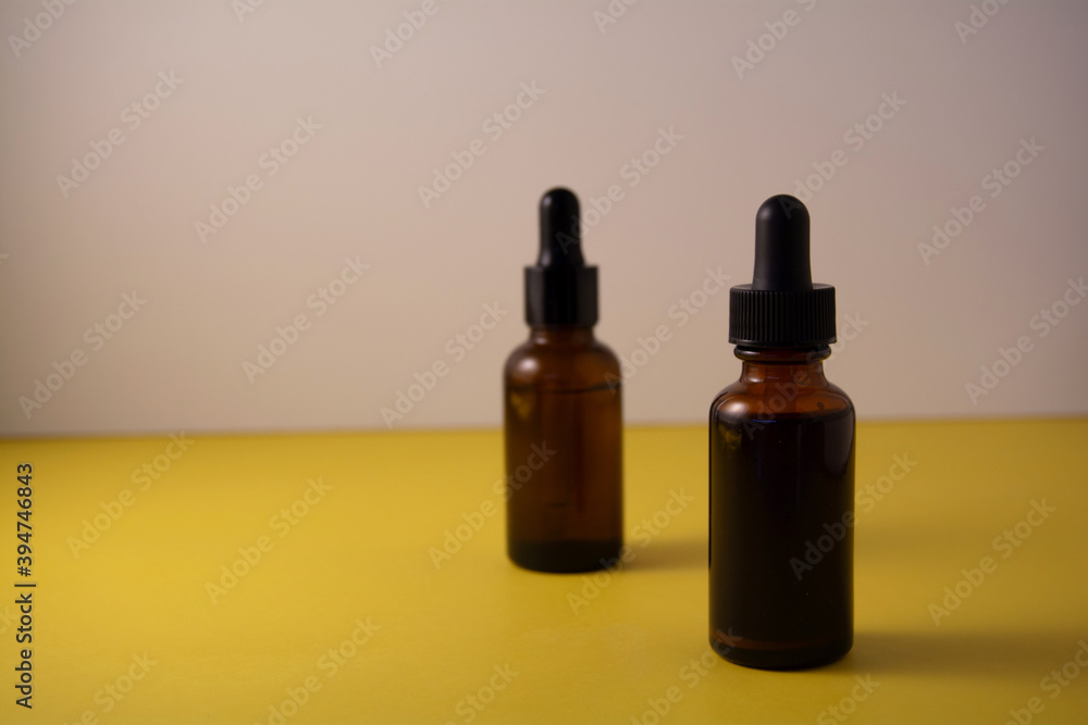 Beauty product concept. Bottle of serum on yellow and white backgrounds. Front view, copy space