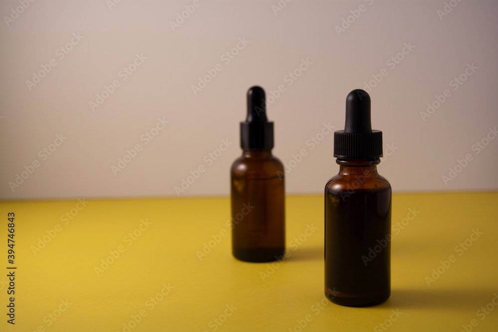 Beauty product concept. Bottle of serum on yellow and white backgrounds. Front view, copy space Beauty product concept. Bottle of serum on yellow and white backgrounds. Front view, copy space