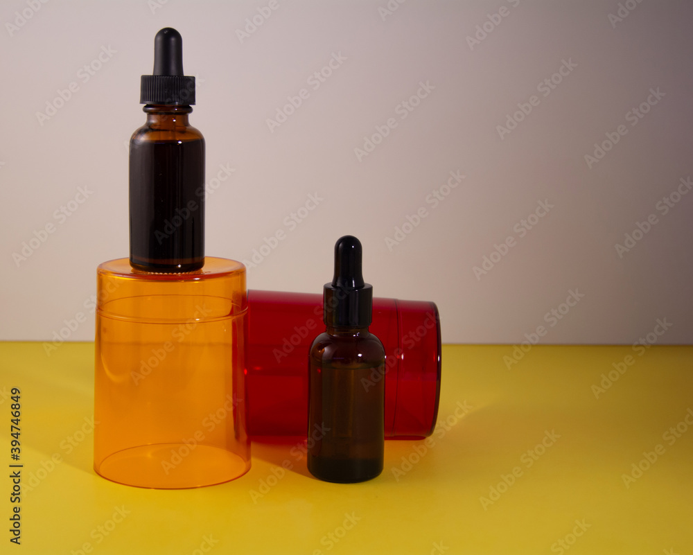 Beauty product concept. Serum bottles on the orange and red transparent podium. Front view