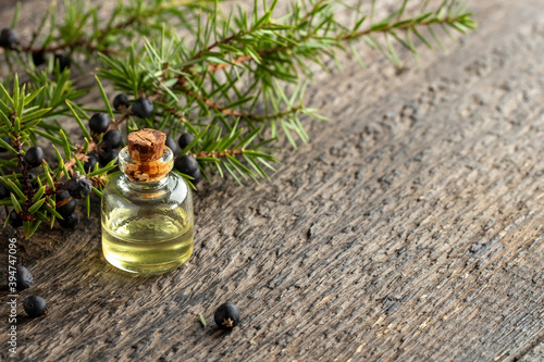 A bottle of essential oil with juniper twigs, with copy space