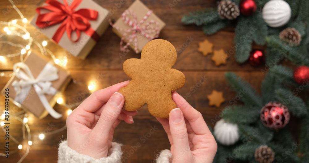 Gingerbread man cookie in hGingerbread man cookie in woman's hands over Christmas background of fir tree, gift boxes and holidays lightsands Gingerbread man cookie in hGingerbread man cookie in woman's hands over Christmas background of fir tree, gift boxes and holidays lightsands