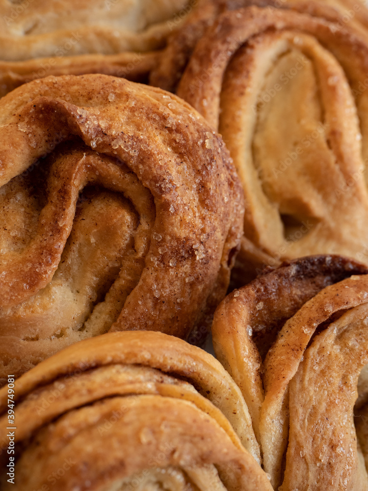Homemade sweet bun with cinnamon and sugar on white paper background Homemade sweet bun with cinnamon and sugar on white paper background