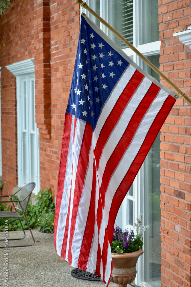 An American Stars and Stripes flag hangs patriotically from a house in small town USA.