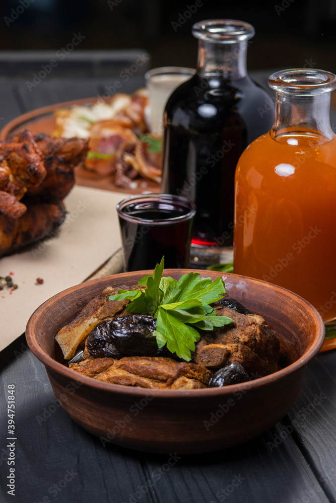 Stewed ribs with prunes in a plate, with wine on black wooden background Stewed ribs with prunes in a plate, with wine on black wooden background