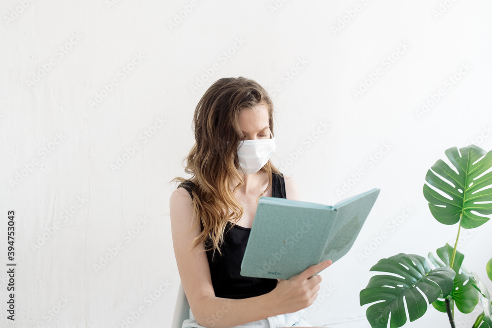 Young woman in protective mask reading distance learning book at home
Young woman in protective mask reading distance learning book at home