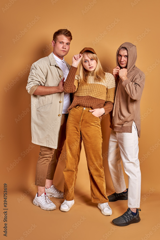 portrait of trendy stylish youth posing at camera isolated on brown background, handsome male and beautiful females in fashionable brown clothes stand together, models portrait of trendy stylish youth posing at camera isolated on brown background, handsome male and beautiful females in fashionable brown clothes stand together, models