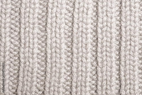 White knitted sweater fragment close-up. White woolen texture. Detailed warm yarn background. Natural woolen fabric.