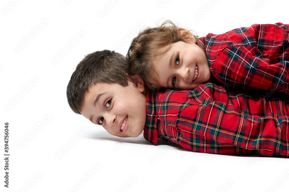 Isolated portrait on white. The little sister is lying on top of her brother, the children are smiling. Isolated portrait on white. The little sister is lying on top of her brother, the children are smiling.