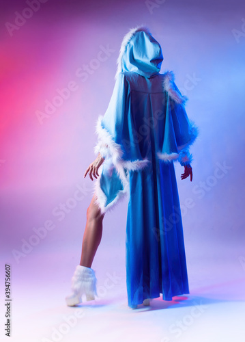 a woman in a blue snow maiden costume poses on a light neon background