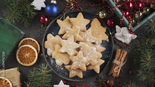 Christmas gingerbread cookies on a blue plate and ingredients for baking, rotate on their axis, top-down view. Baking for the holiday. Presenting cookies on a plate, holiday plating.