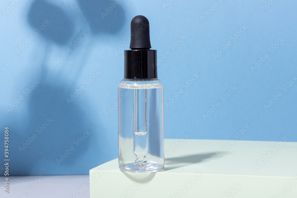 Cosmetic glass bottle with dropper on podium with hard shadows. The concept of a beauty salon and natural cosmetics. Cosmetic glass bottle with dropper on podium with hard shadows. The concept of a beauty salon and natural cosmetics.