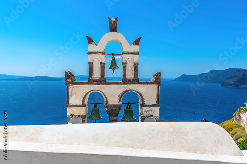 The bell tower of a church in the village of Oia, Santorini highlighted against the backdrop of the caldera in summertime