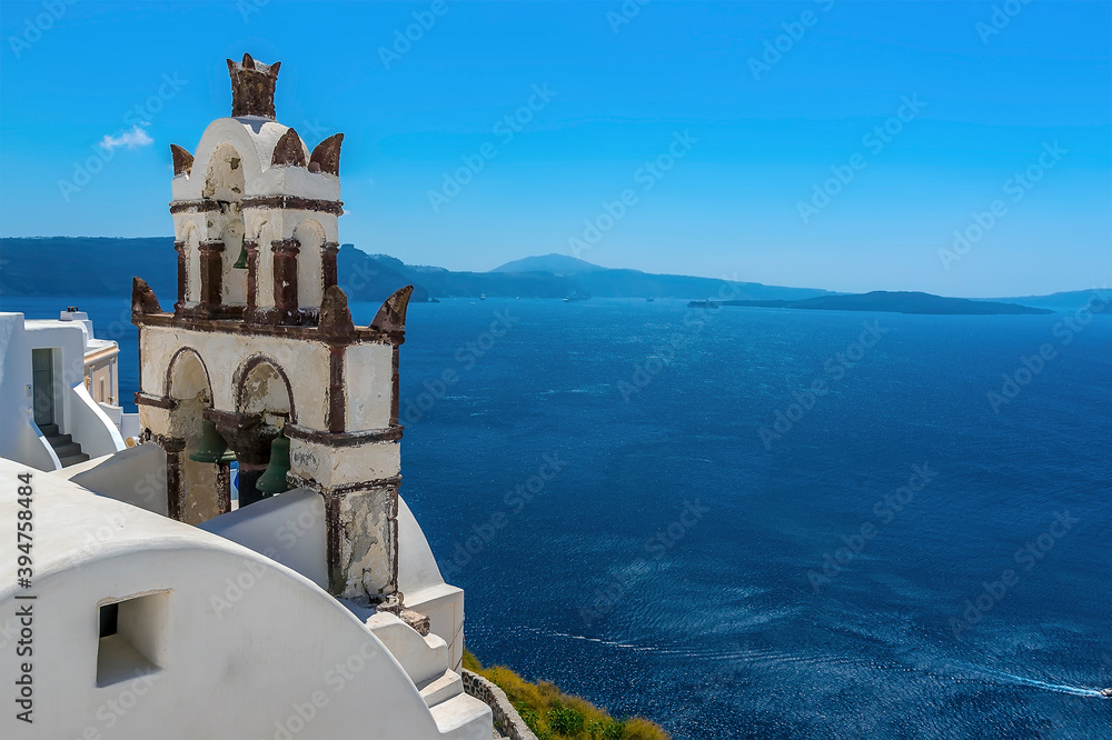 The bell tower of a church in the village of Oia, Santorini overlooks the caldera in summertime