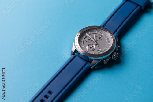 Reloj de pulsera plateado con correa azul sobre fondo azul cielo, con espacio para texto. Accesorios para hombre.