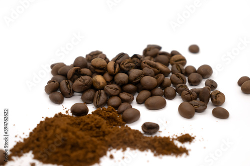 Ground coffee with plastic white spoon and coffee beans isolated on white background.