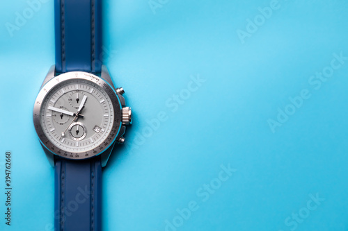 Reloj de pulsera plateado con correa azul sobre fondo azul cielo, con espacio para texto. Accesorios para hombre.