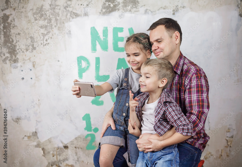 Father with kids planning new year with checklist on wall and making selfie with smartphone