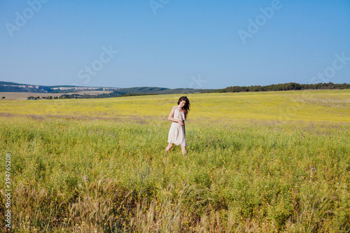 Beautiful woman in dress walks on the field happily one