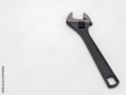 Black open adjustable wrench on a light background