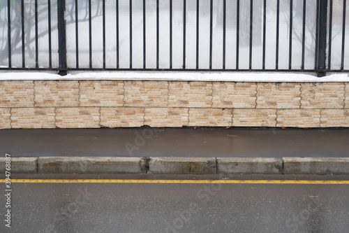 Sidewalk and curb wet from the rain and a metal fence, minimalism
