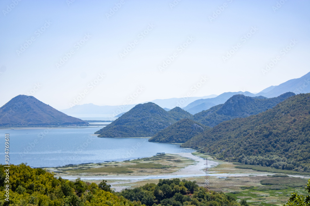A beautiful view of the Skadar (Skoderskoe) lake among the mountains. This section of the lake is overgrown with tall grass. Montenegro.